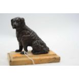 A bronzed model of a seated spaniel, having adjustable clip mouth, mounted upon a polished hardstone