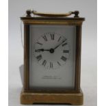 A 20th century lacquered brass cased carriage clock having an enamel dial with Roman numerals,