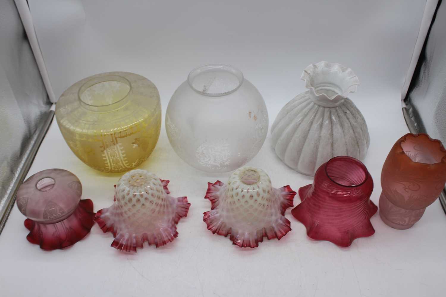 A collection of 19th century and later glass oil lamp shadesTwo floral white with cranberry