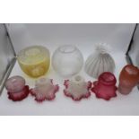 A collection of 19th century and later glass oil lamp shadesTwo floral white with cranberry