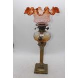 A Victorian brass oil lamp, the amber tinted shade above an amber tinted font and corinthian