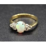 An 18ct gold, opal and diamond dress ring, arranged as a cabochon opal measuring approx 7 x 5.5mm,