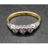 An 18ct gold and platinum diamond three stone ring, the small illusion set round cuts in a line