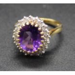 An 18ct gold, amethyst and diamond cluster ring, the oval cut amethyst measuring approx 11.5 x