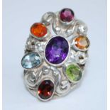 A sterling silver multi-stone dress ring, having a centre oval faceted amethyst bezel set within