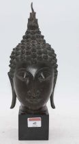 A bronze buddha head, mounted upon a polished black hardstone plinth, height 32cm