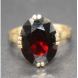 A modern yellow metal garnet set dress ring, the four claw set oval cut garnet measuring approx