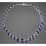 A contemporary silver and sapphire set necklace, arranged as 31 faceted oval bezel set sapphires,