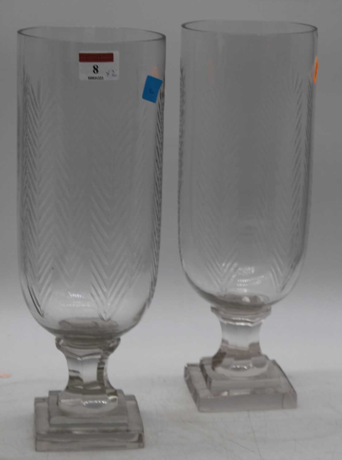 A pair of cut glass hurricane lamps, each on faceted stem and stepped plinth, height 34cm