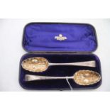 A pair of 19th century silver berry spoons, having embossed gilt washed bowls with bright cut