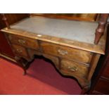 An early 20th century figured walnut and rexine inset kneehole writing table, having an