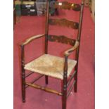 An Arts & Crafts oak and rush seat pierced ladder back single elbow chair, width 55cm