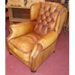 A contemporary tan leather upholstered brass studded and button back wing scroll club chair raised