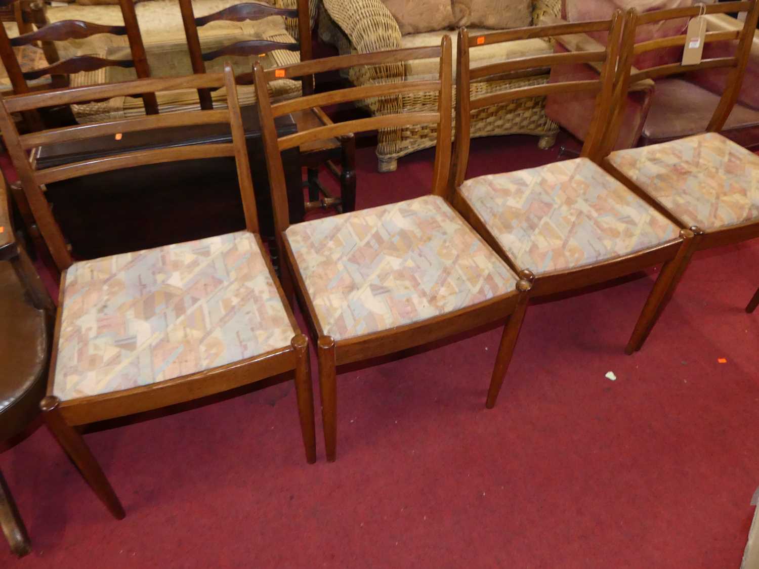 A set of four 1960s G-Plan teak ladder back dining chairs, having bright coloured fabric upholstered