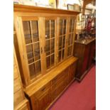 A contemporary American cherry wood dresser, having four glazed upper doors, shelved interior,