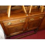 An early 20th century small oak two-door sideboard, having twin upper drawers and raised on part