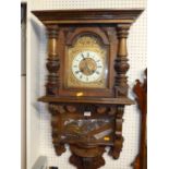 A circa 1900 Austrian carved walnut drop trunk wall clock, having arched enamel and gilt decorated