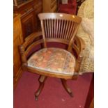 A late Victorian walnut slat back tub swivel elbow desk chair, raised on slightly hipped outswept