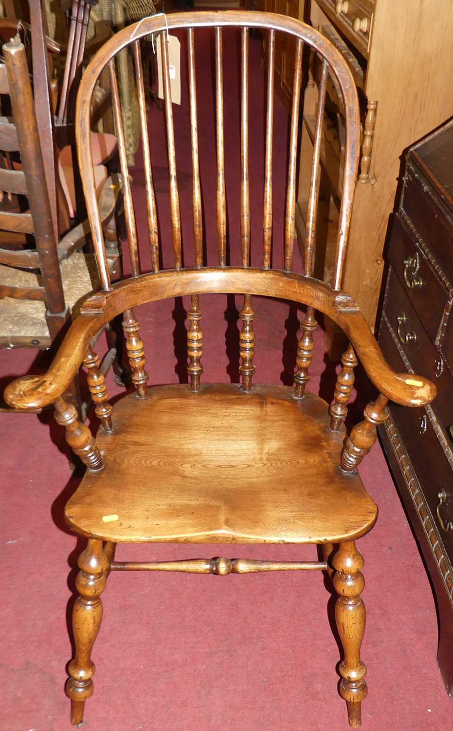 An elm, beech and fruit wood comb back Windsor chair, raised on turned supports to H-stretcher,