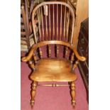 An elm, beech and fruit wood comb back Windsor chair, raised on turned supports to H-stretcher,