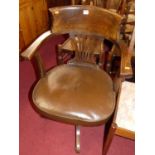 A 1930s beech splat and tub back swivel desk elbow chair, having a tan rexine upholstered stuff-over