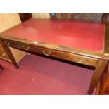 An early 20th century mahogany and rexine inset two drawer library writing table, raised on square