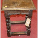 An antique joined oak joint stool raised on bobbin turned supports, united by square lower