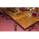An early 20th century oak plank top refectory table having draw-leaf end extensions, raised on