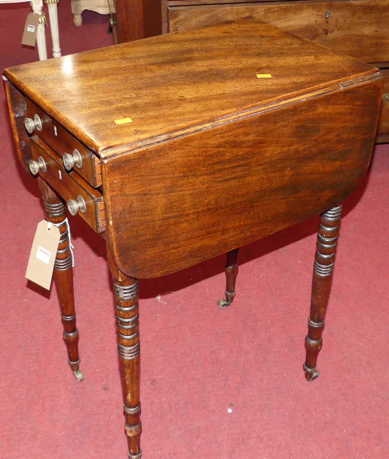 An early 19th century mahogany drop-flap two drawer work table, on ring turned supports