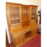 A contemporary pitched pine kitchen dresser, having twin glazed upper doors (one pane damaged), open