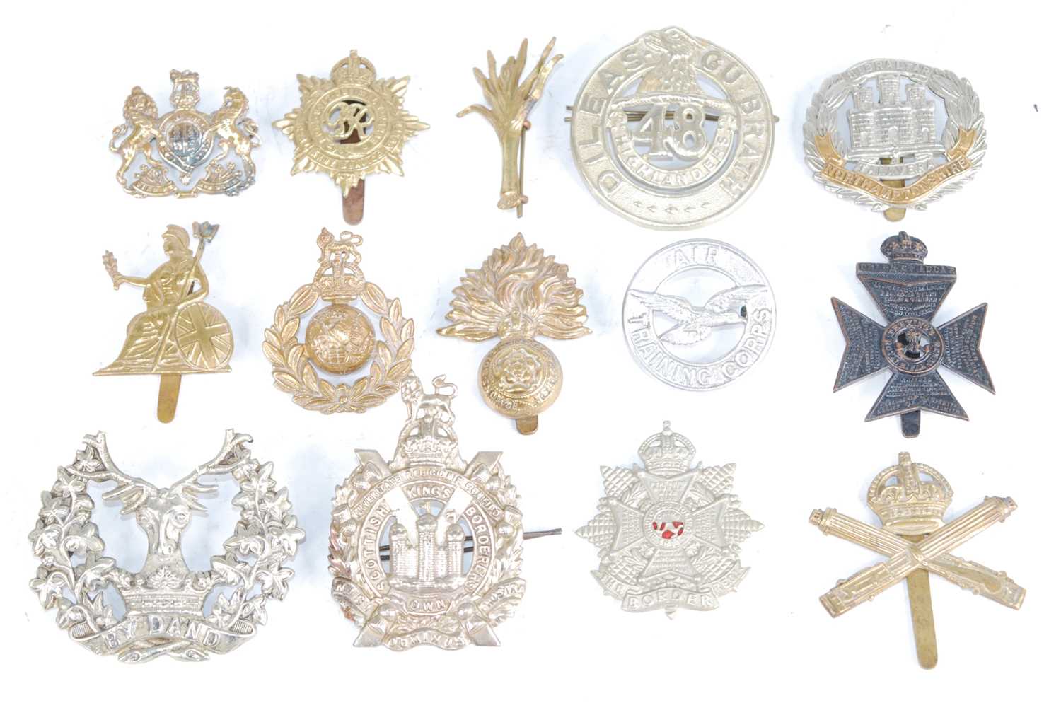 A collection of cap badges and insignia to include The King's Own Scottish Borderers,
