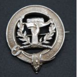 A 20th century white metal clan badge, possibly for the Buchanan Clan, the central hand within a
