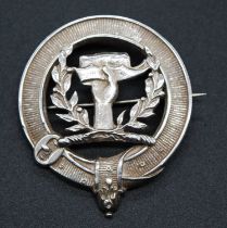 A 20th century white metal clan badge, possibly for the Buchanan Clan, the central hand within a