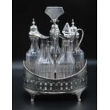 A George III white metal five bottle cruet stand, of pierced oval form with mahogany base, the