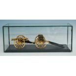 A lacquered brass scale model of a Napoleonic cannon and carriage, mounted on an ebonised plinth