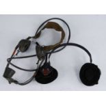 A pair of military headphones, having a canvas head strap and adjustable mouthpiece, together with