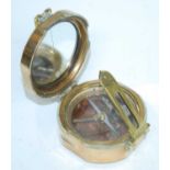 A WW II brass cased Brunton style military compass the hinged mirrored lid revealing compass and