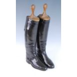 A pair of black leather calf length riding boots with wooden trees.
