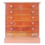 A Victorian stained pine collectors chest of six short drawers on a plinth base containing various