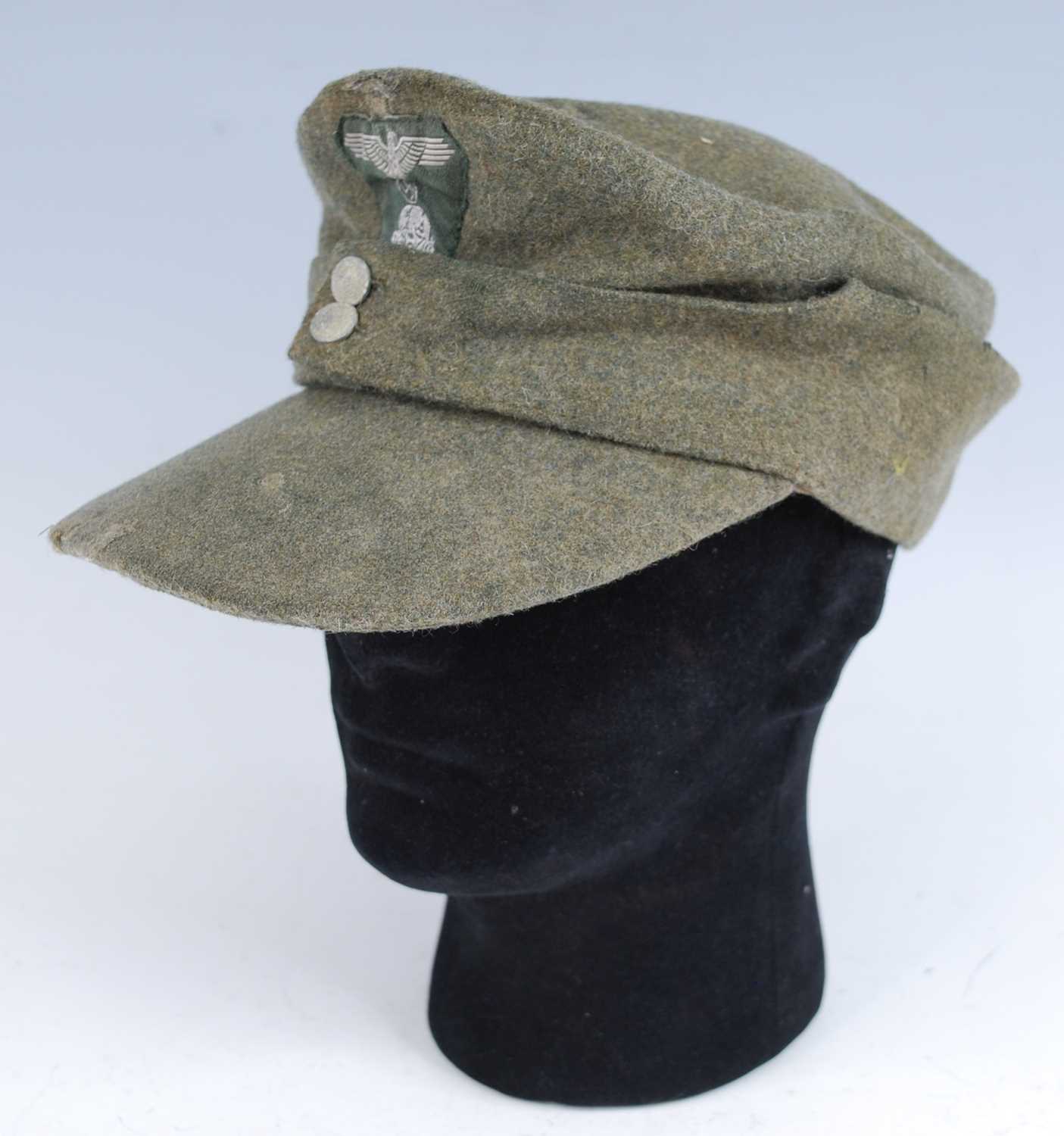 A German M43 SS Field cap, in green wool with stitched badge, the interior stamped SS-BW, dated