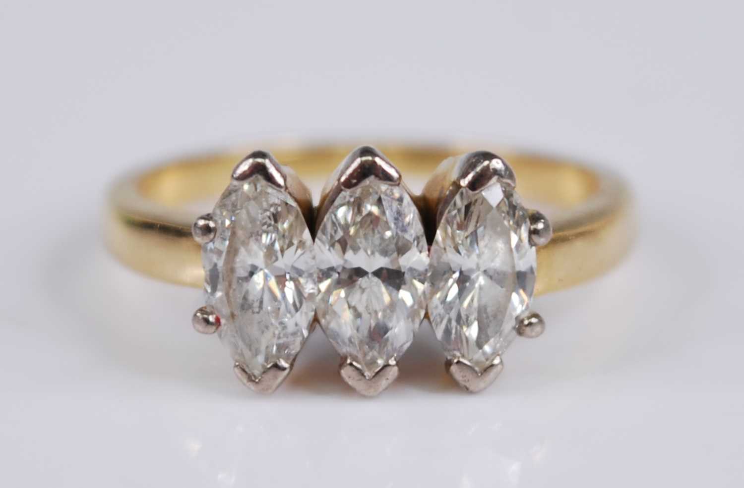 A yellow metal diamond three stone ring, the claw set marquise cut diamonds in a line setting, - Image 2 of 5