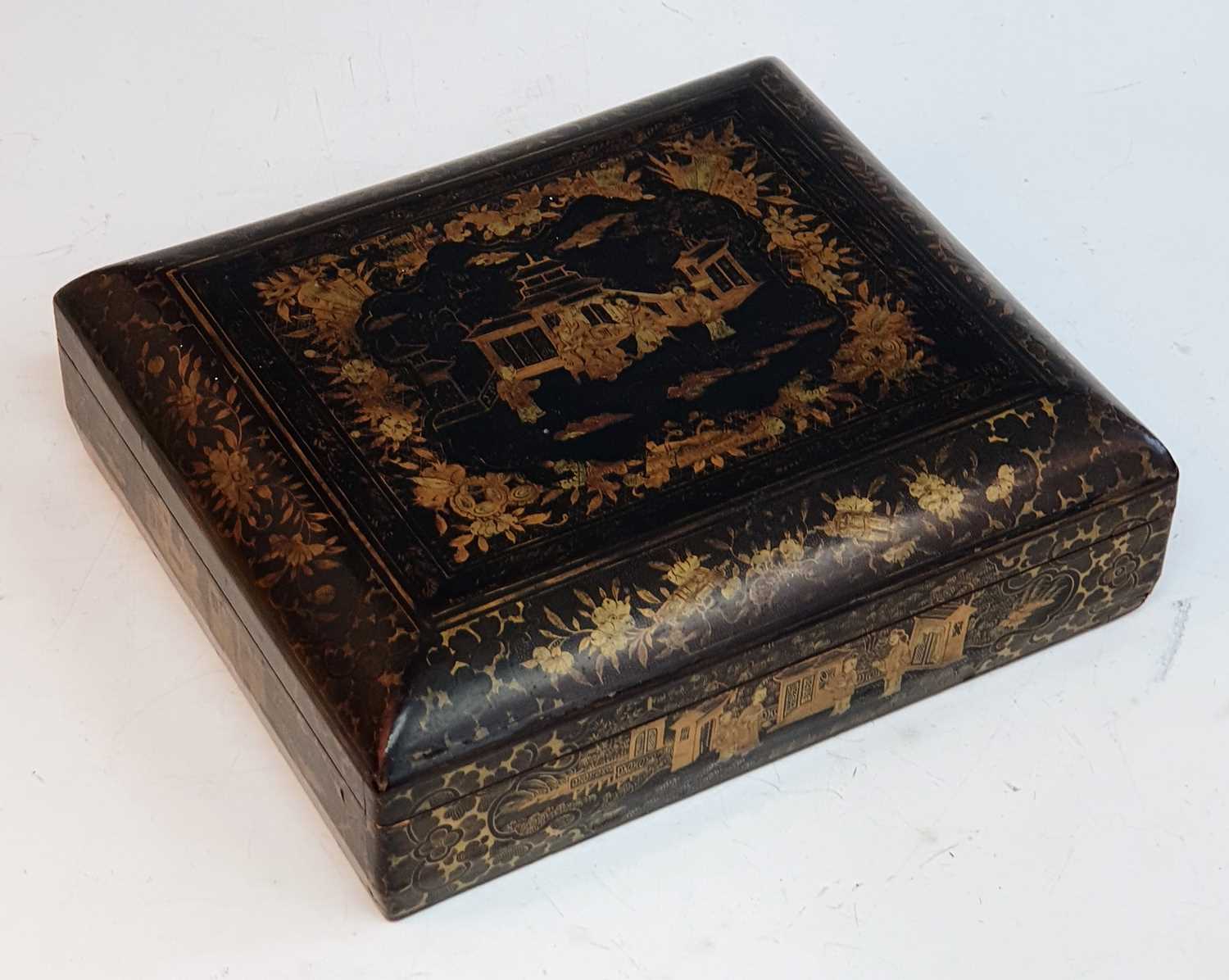 A 19th century Chinese lacquered games box, the lid decorated with figures before a pagoda lifting