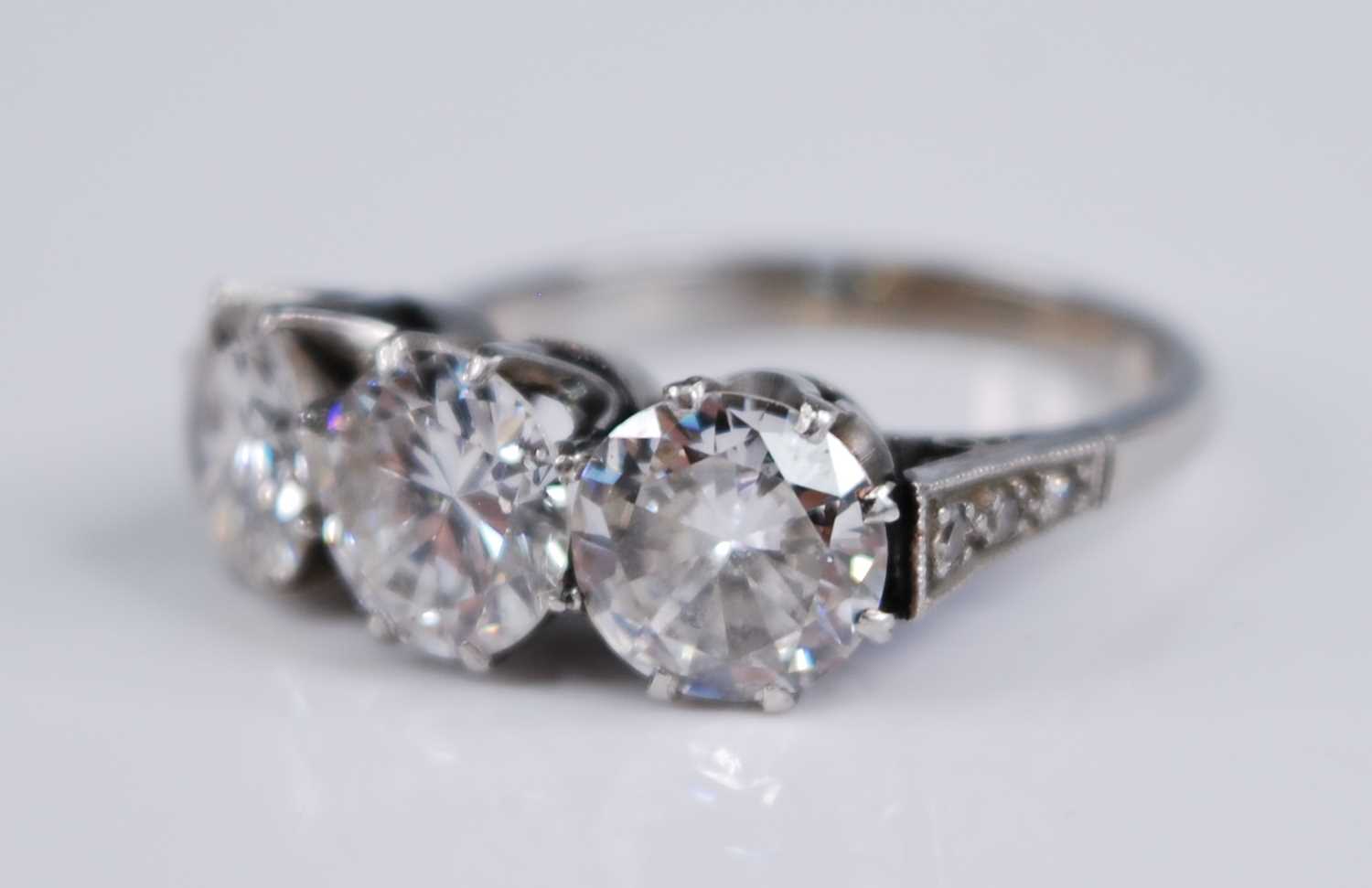 A white metal diamond three stone ring, comprising three round brilliant cut diamonds in claw - Image 3 of 7