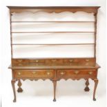 An 18th century oak Welsh dresser, the four-tier open plate rack having two short lower drawers over