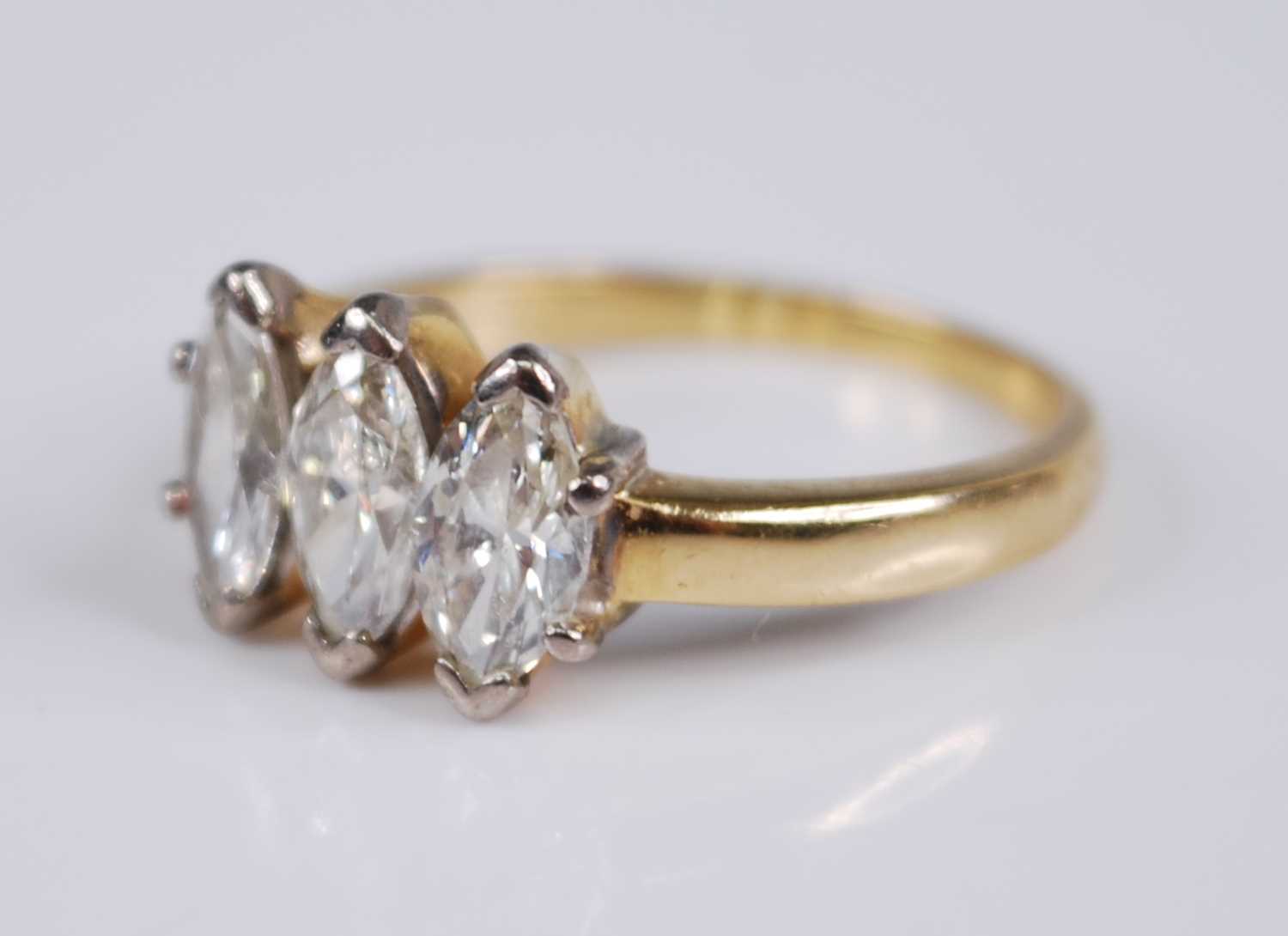 A yellow metal diamond three stone ring, the claw set marquise cut diamonds in a line setting, - Image 3 of 5