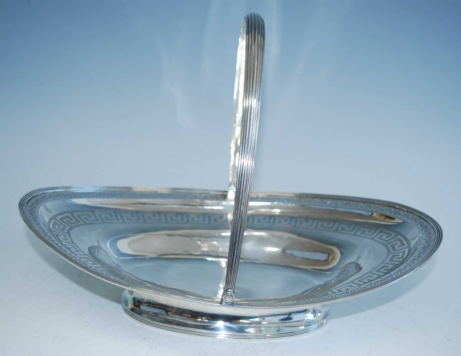 A George III silver pedestal bread basket, of elliptical form with reeded rim and reeded swing