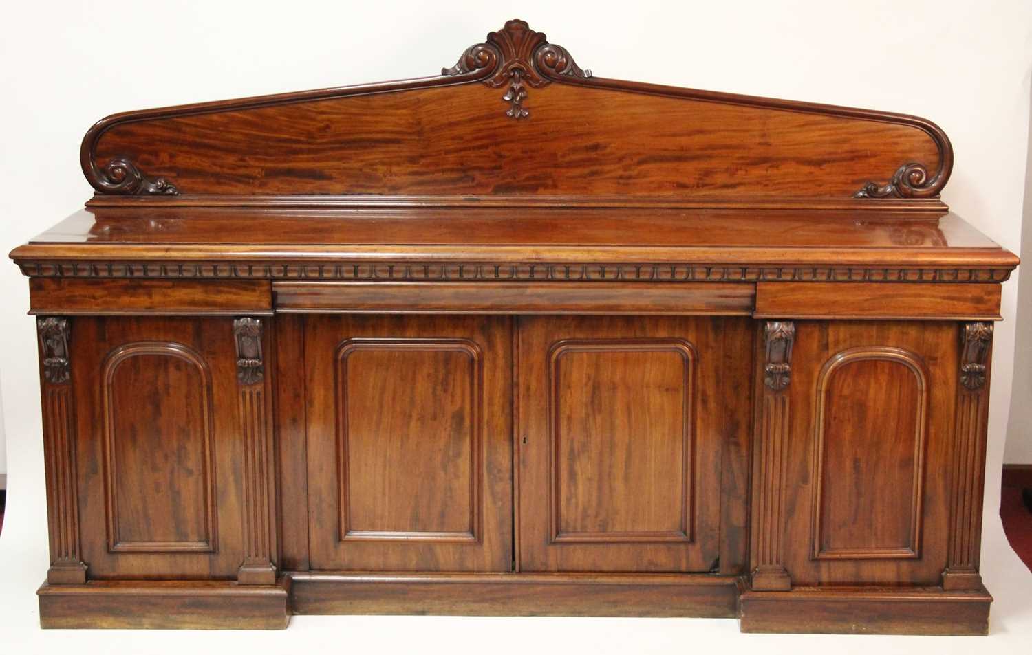 An early Victorian plum-pudding mahogany ledgeback sideboard, having floral carved detail, egg and