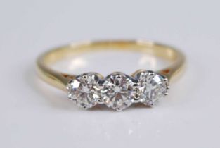 An 18ct yellow and white gold diamond three stone ring, featuring three graduated round brilliant