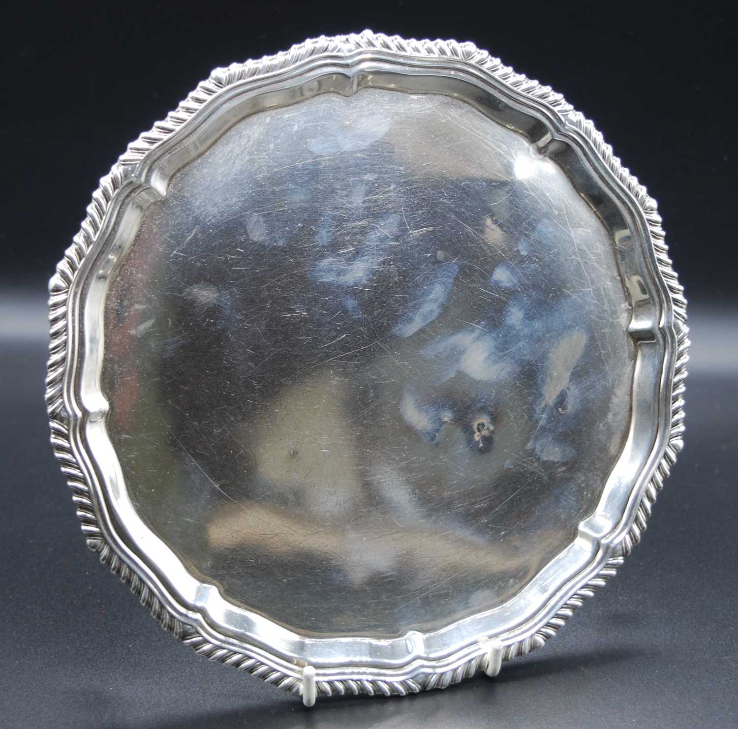 A George V silver card waiter, of shaped circular form with a gadrooned piecrust rim, standing