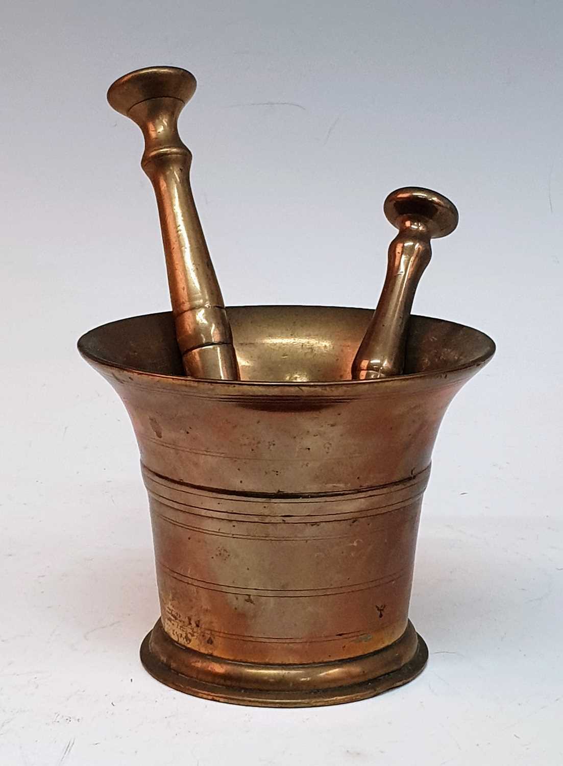 An 18th century bronze mortar, of plain tapered form, h.11cm, together with two bronze pestles